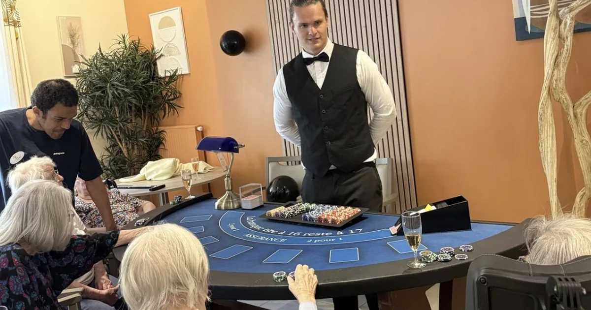 Croupier animant la table de blackjack devant des résidents réunis autour du tapis, lors de la journée casino à l'EHPAD Le Clos des Meuniers à Bagneux